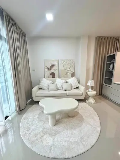 Modern living room with elegant white sofa, abstract art, and stylish round rug.