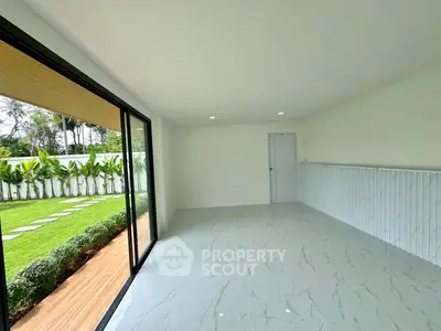 Spacious room with large sliding glass doors opening to a lush garden, perfect for indoor-outdoor living.