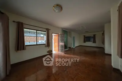 Spacious living room with wooden flooring and ample natural light, perfect for family gatherings.
