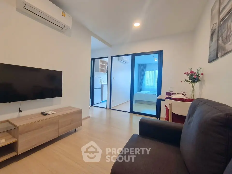 Modern living room with sleek furniture and open view to bedroom, featuring air conditioning and stylish decor.