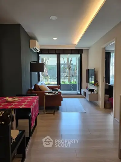 Modern living room with stylish decor and large windows overlooking greenery.