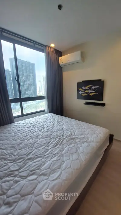 Modern bedroom with large window and city view, featuring air conditioning and stylish decor.