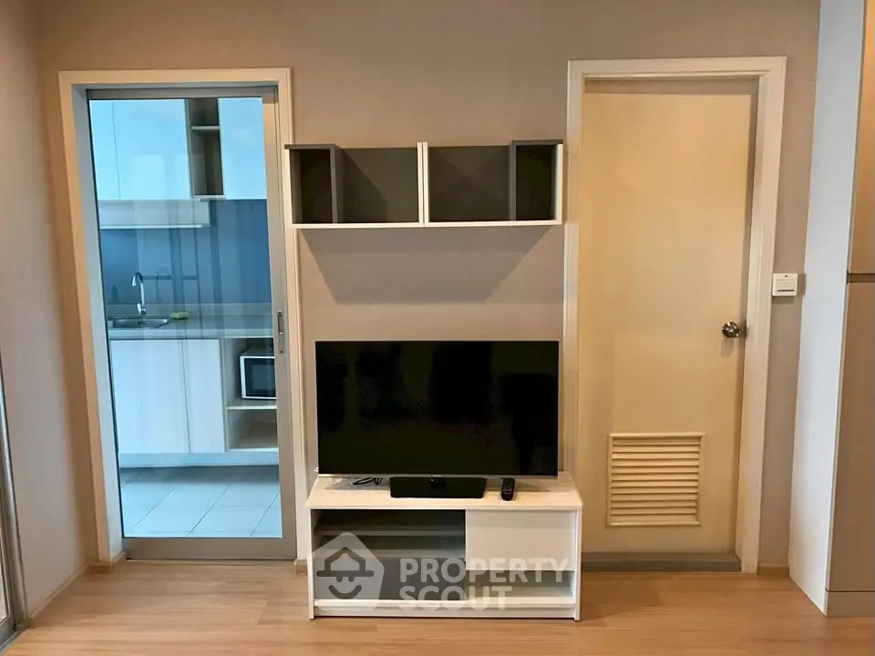 Modern living room with sleek TV stand and view into contemporary kitchen