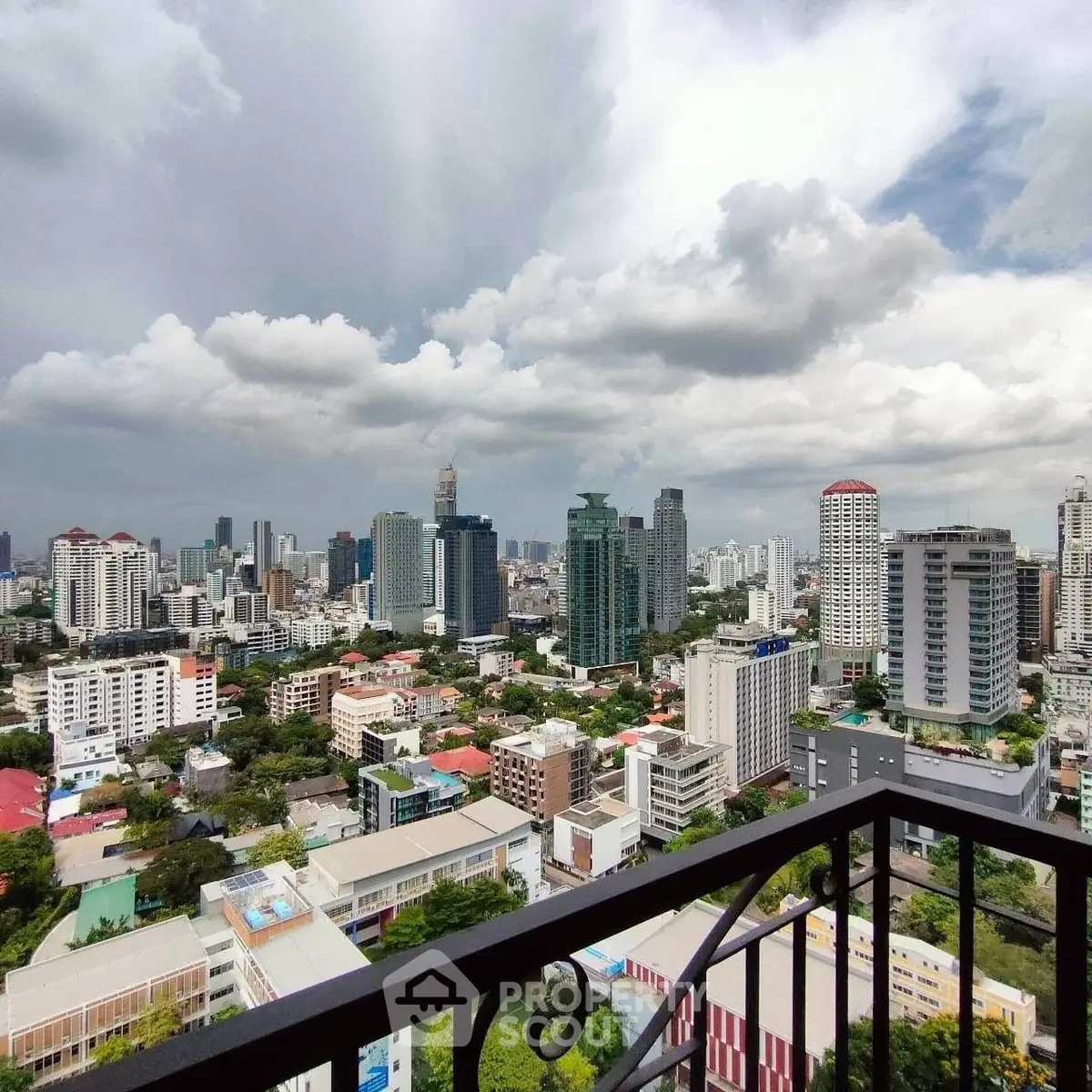 Stunning cityscape view from a high-rise balcony showcasing urban skyline and lush greenery.