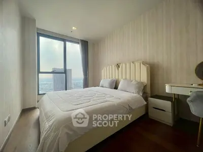 Luxurious bedroom with stunning city view from large window, elegant furnishings, and cozy ambiance.