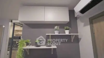 Modern kitchen interior with sleek cabinets and decorative plants on shelves.