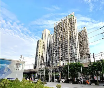 Modern high-rise residential building with lush greenery and clear blue sky.