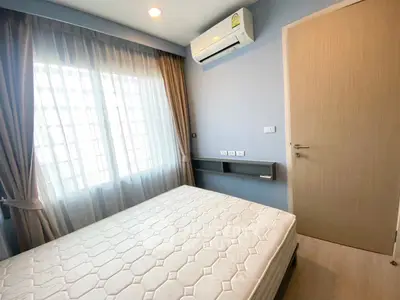 Cozy bedroom with natural light, featuring a comfortable bed and modern air conditioning unit.