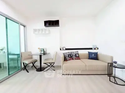 Modern living room with beige sofa and dining area in open layout apartment.