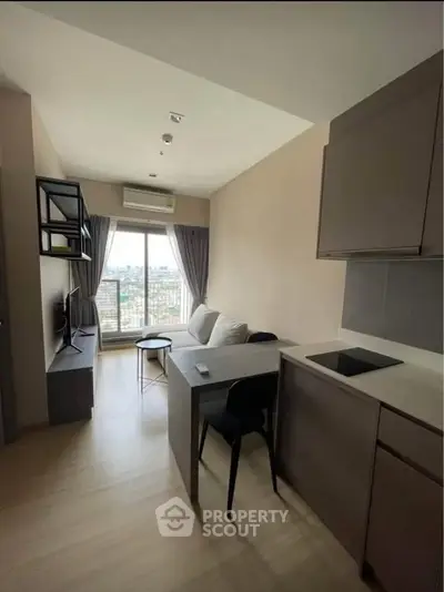 Modern living room with open kitchen and city view, featuring sleek furniture and natural light.