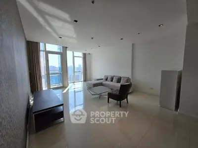 Spacious modern living room with large windows and city view, featuring sleek furniture and abundant natural light.