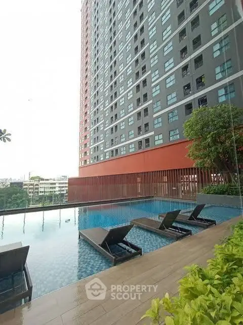 Modern apartment building with pool and lounge chairs, perfect for urban living.