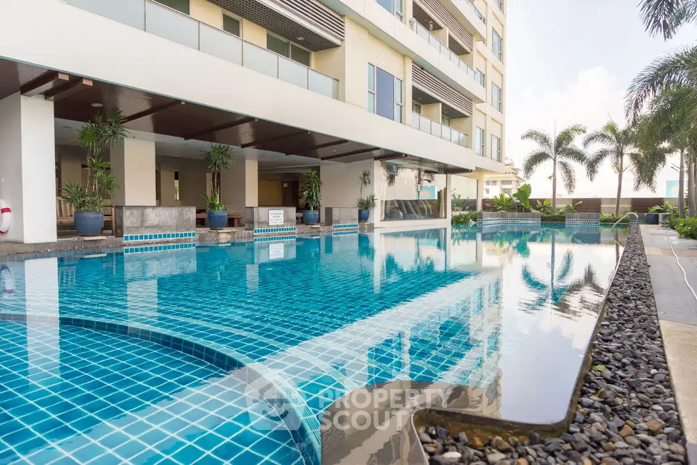 Luxurious apartment building with stunning pool and palm trees, perfect for relaxation and leisure.