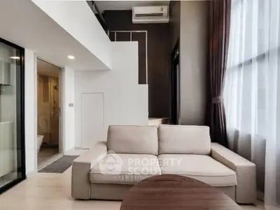 Modern living room with beige sofa and large windows in stylish apartment