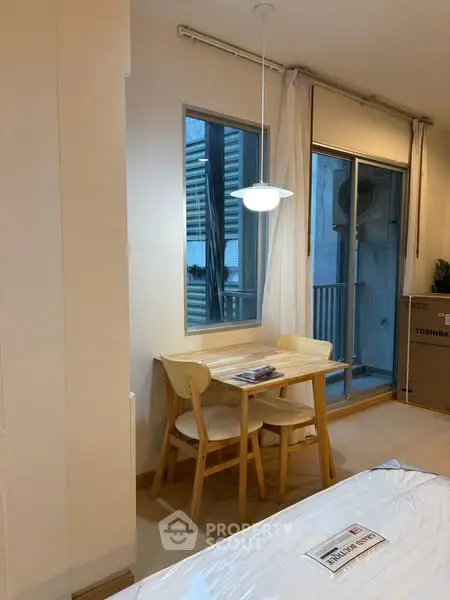 Cozy dining nook with wooden table and chairs next to a window in a modern apartment.