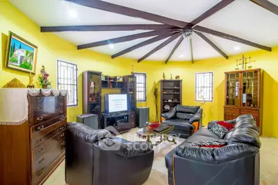 Spacious living room with vibrant yellow walls and stylish black leather furniture.