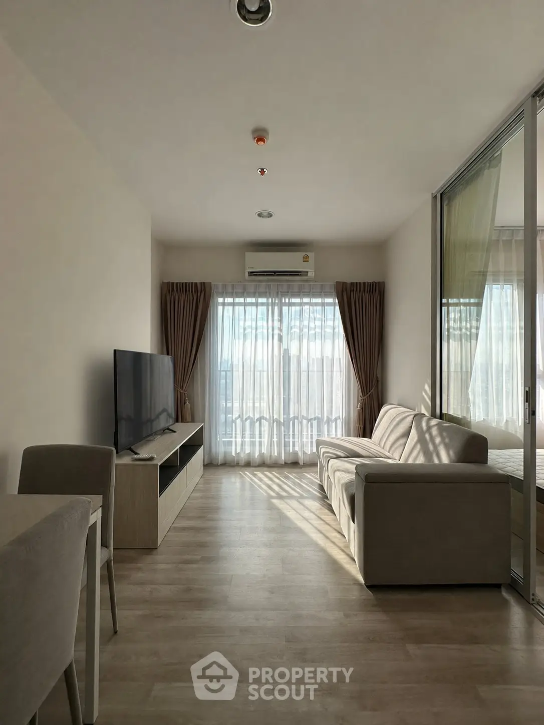 Modern living room with natural light, featuring a sleek sofa and large TV, perfect for relaxation.