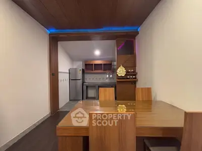 Modern dining area with wooden furniture and open kitchen layout in a cozy apartment.