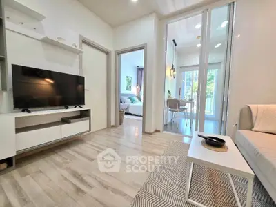 Modern living room with sleek design and natural light, featuring a TV and stylish furniture.
