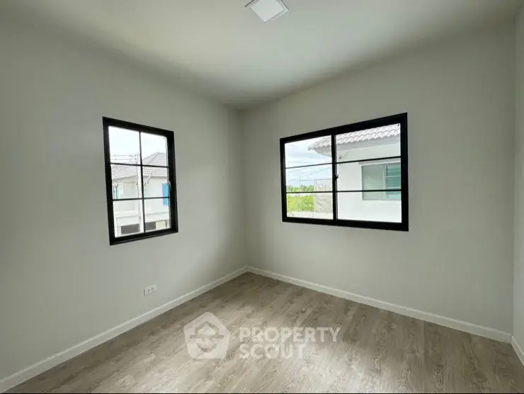 Bright empty room with large windows and wooden flooring, perfect for customization.