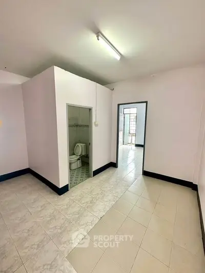 Spacious interior with tiled flooring and bathroom access, ideal for modern living.
