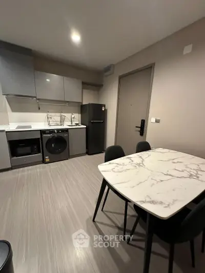 Modern kitchen with sleek appliances and stylish dining area in contemporary apartment.