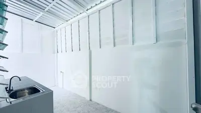 Minimalist white kitchen with stainless steel sink and open layout