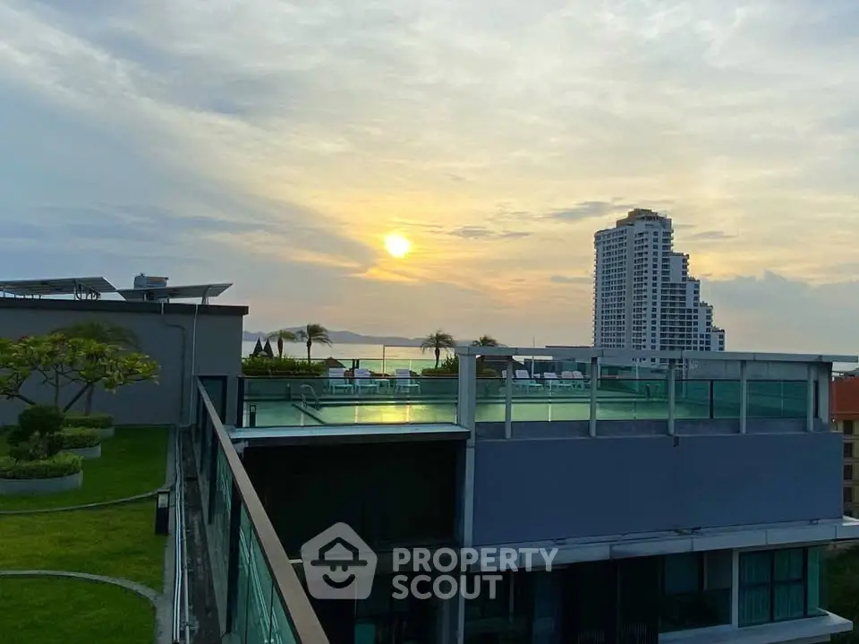 Stunning rooftop view with pool and sunset over the city skyline.