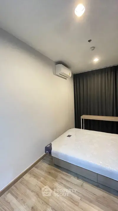 Modern bedroom with minimalist design, featuring a comfortable bed and sleek air conditioning unit.