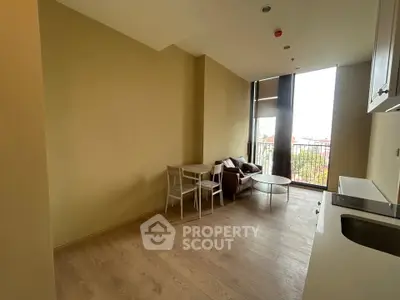 Modern living room with open kitchen and large windows offering city views.