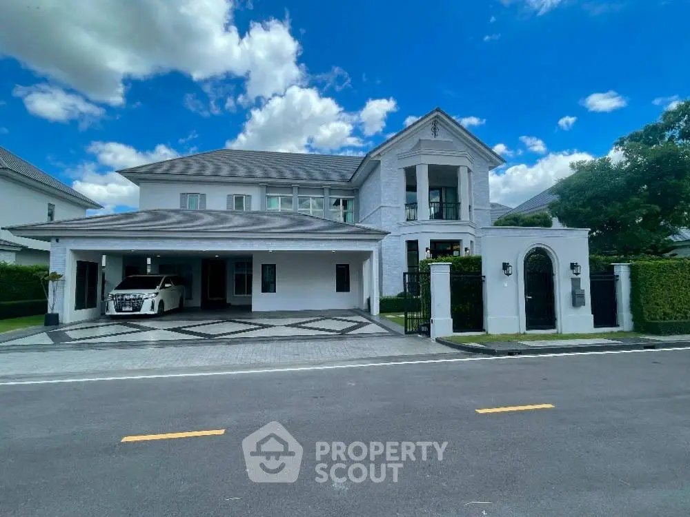 Luxurious modern mansion with spacious driveway and elegant architecture under a clear blue sky.