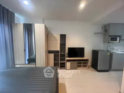 Modern studio apartment with sleek furniture and compact kitchen area, perfect for urban living.