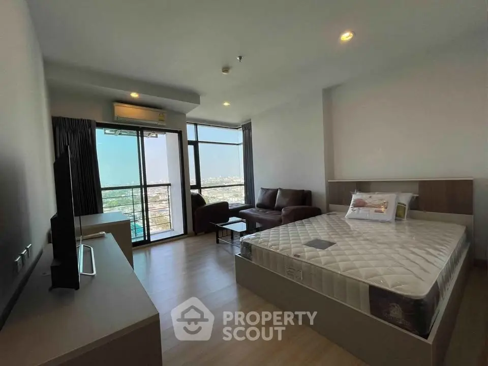Spacious bedroom with city view, featuring modern furniture and large windows for natural light.