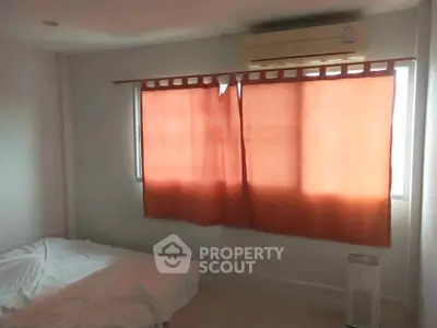 Cozy bedroom with air conditioning and natural light through red curtains.