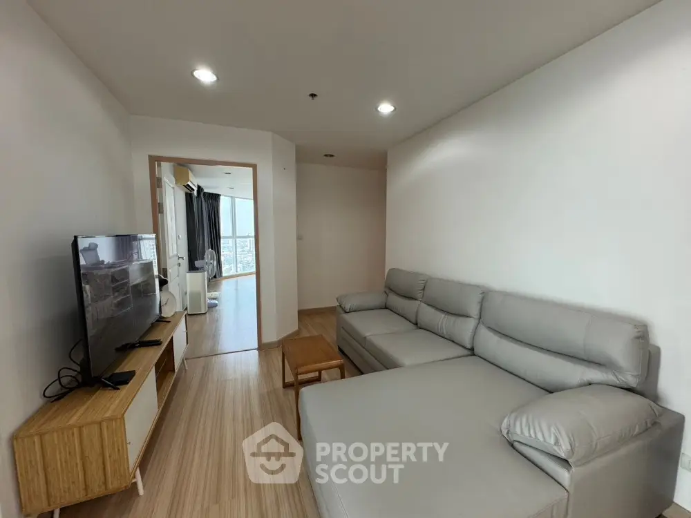Modern living room with sleek furniture and wooden flooring in a high-rise apartment.