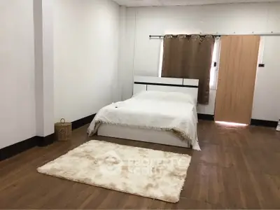 Spacious minimalist bedroom with wooden flooring and cozy decor