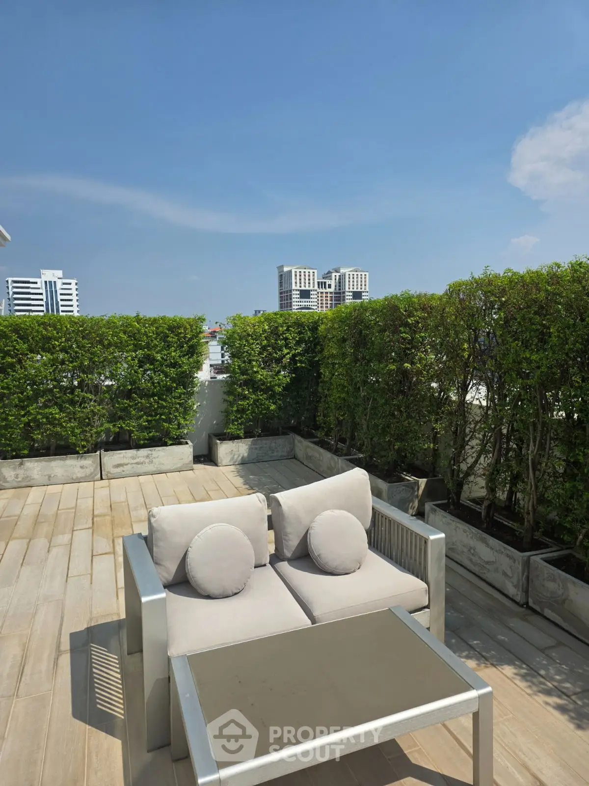 Luxurious rooftop terrace with modern seating and lush greenery, offering stunning city views.