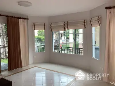 Spacious corner unit with large windows and elegant curtains in a bright living room.