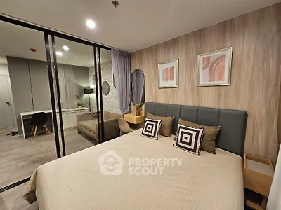 Modern bedroom with stylish decor and glass partition, featuring a cozy bed and elegant artwork.