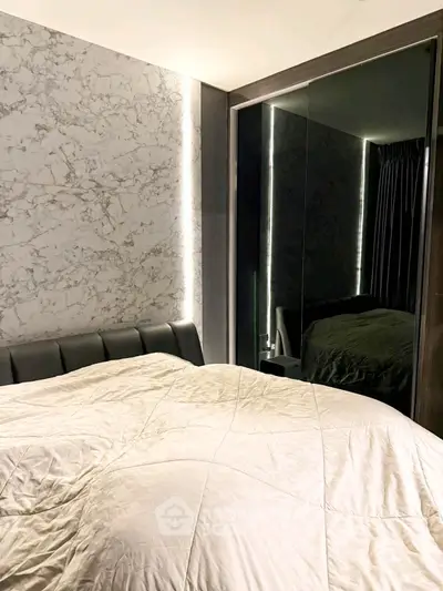 Luxurious bedroom with marble accent wall and mirrored wardrobe