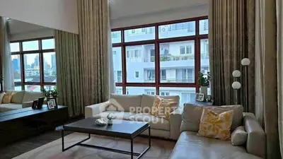 Spacious living room with large windows and modern decor, offering a cozy and inviting atmosphere.