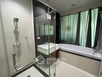 Modern bathroom with glass shower and bathtub, elegant design and natural light.