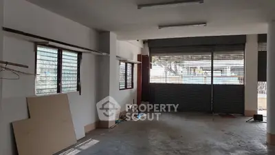 Spacious garage or storage area with large windows and roller shutter doors.