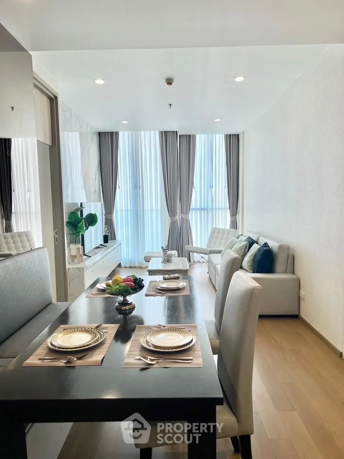 Elegant modern living room with dining area, featuring large windows and stylish decor.