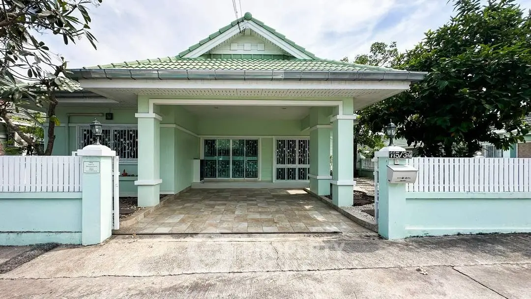 Charming mint green house with tiled driveway and white picket fence