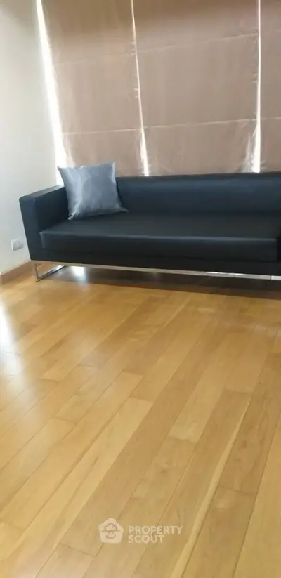 Modern living room with sleek black sofa and wooden flooring