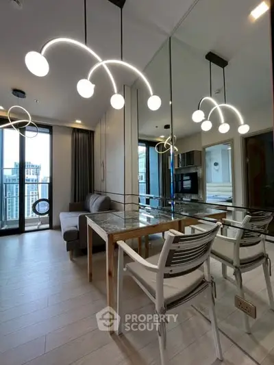 Modern living room with stylish lighting and mirrored wall, featuring a cozy sofa and dining area.