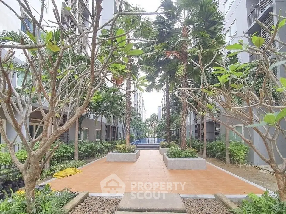 Modern apartment complex with lush garden and walkway, offering serene outdoor living space.