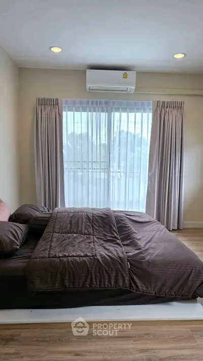 Cozy bedroom with large window and elegant curtains, featuring a comfortable bed and modern air conditioning.
