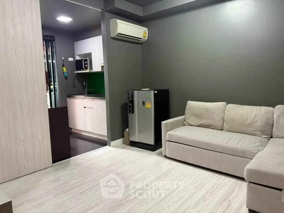 Modern living room with sleek kitchen, featuring air conditioning and stylish furniture for a cozy urban lifestyle.